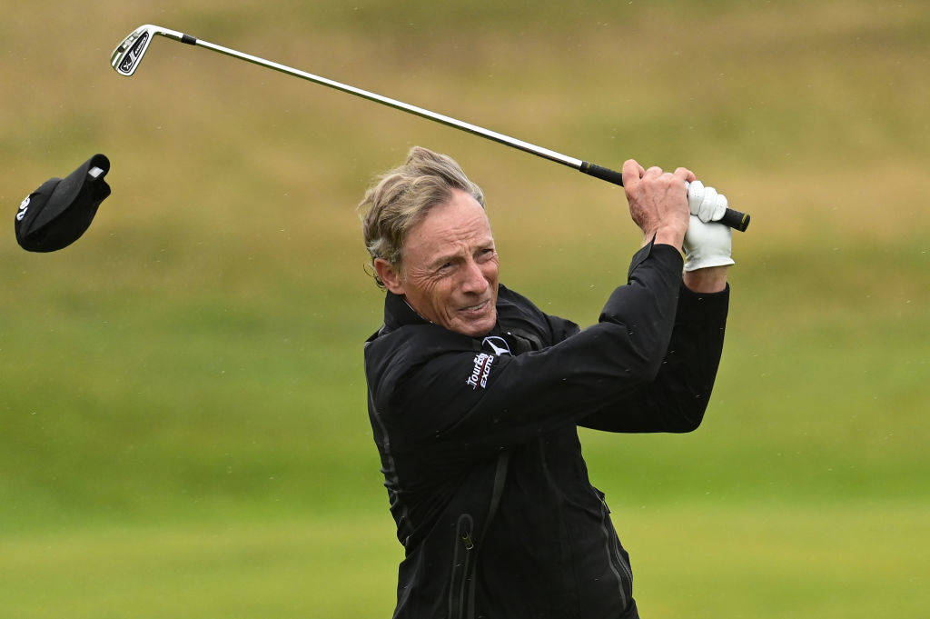 Bernhard Langer of Germany loses his cap as he hits an approach shot on the 2nd hole during Day Four of The Senior Open